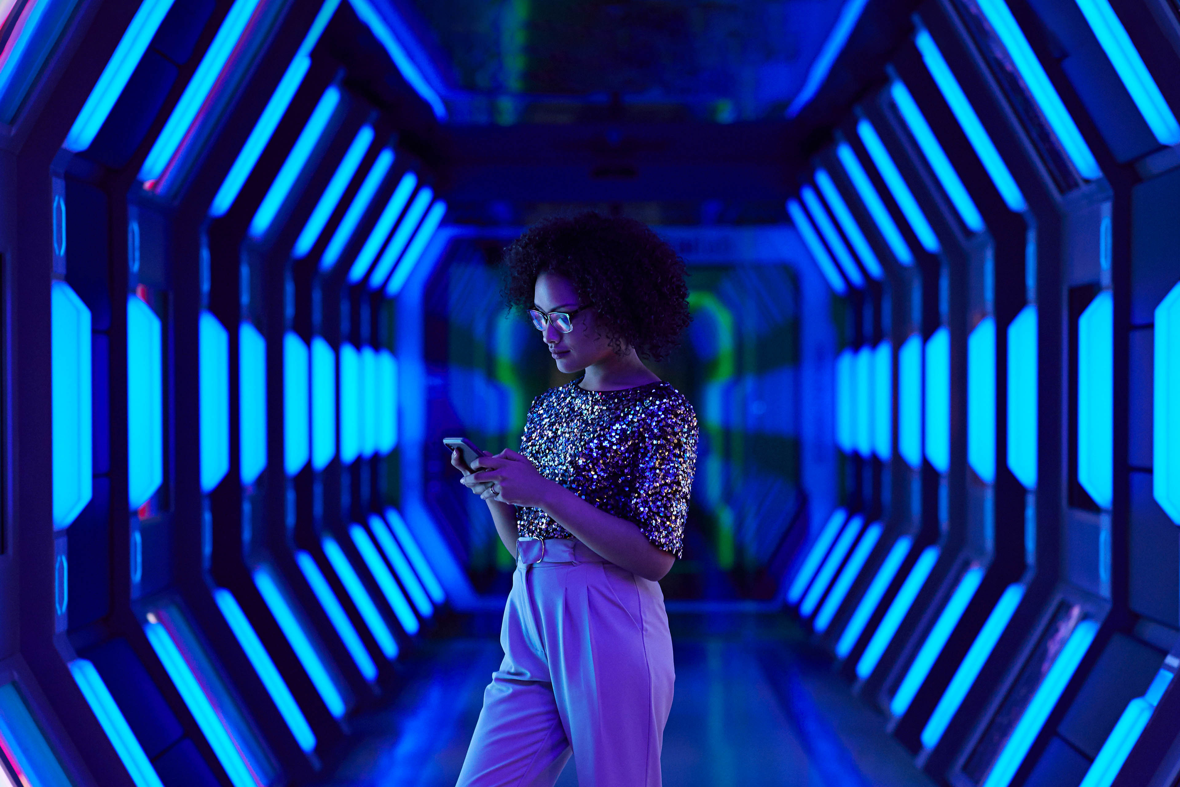 Young businesswoman looking at smartphone in spaceship like corridor